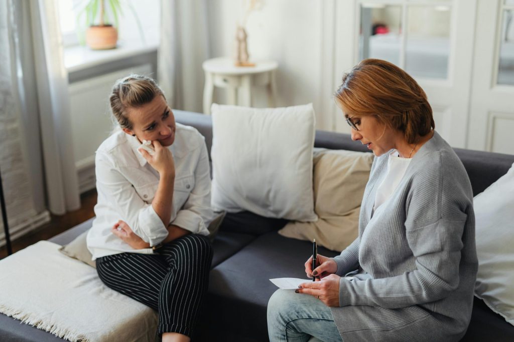A thoughtful therapy session between two women in a cozy room.