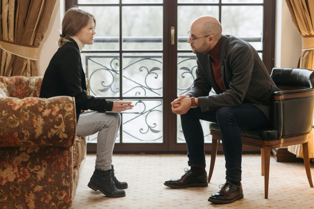 A thought-provoking therapy session with therapist and client discussing in a cozy room.